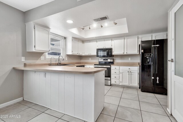 kitchen featuring light countertops, a sink, a raised ceiling, a peninsula, and black appliances