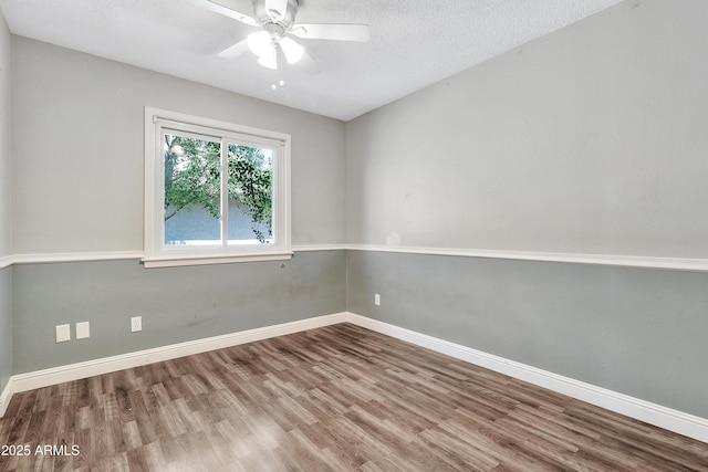 empty room featuring baseboards, wood finished floors, ceiling fan, and a textured ceiling