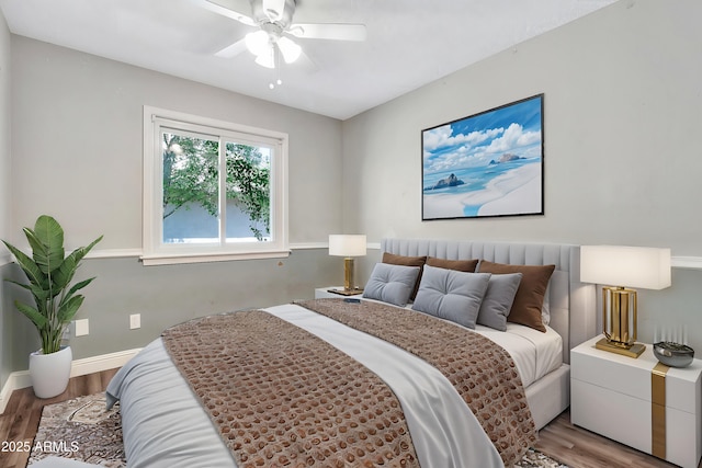 bedroom featuring baseboards, wood finished floors, and a ceiling fan