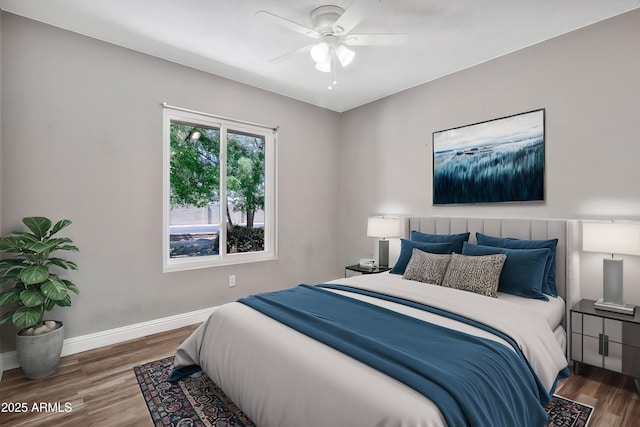 bedroom featuring baseboards, wood finished floors, and a ceiling fan