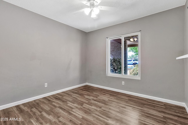 empty room featuring baseboards, wood finished floors, and a ceiling fan