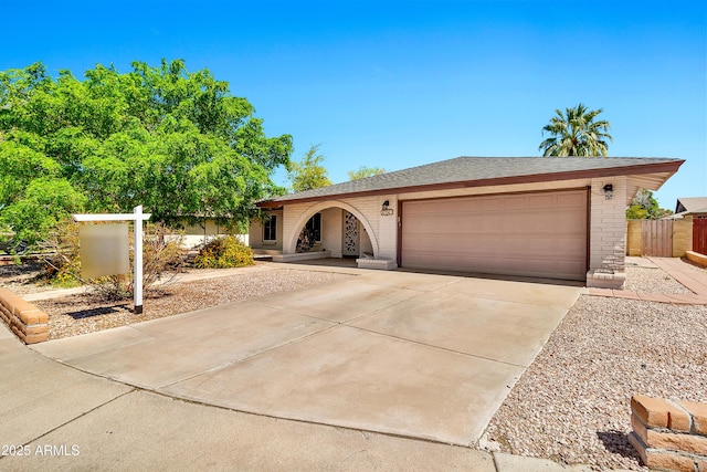 single story home with brick siding, driveway, fence, and a garage