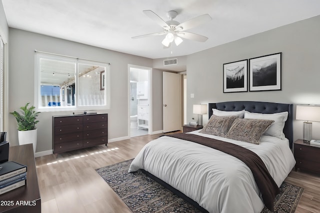 bedroom with wood finished floors, ensuite bath, baseboards, visible vents, and ceiling fan