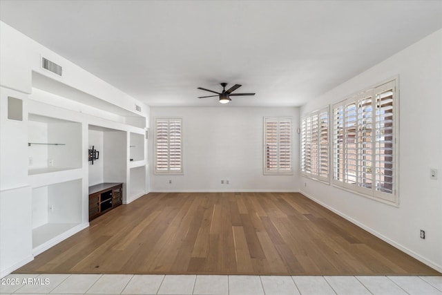 unfurnished living room with ceiling fan, plenty of natural light, light hardwood / wood-style floors, and built in shelves