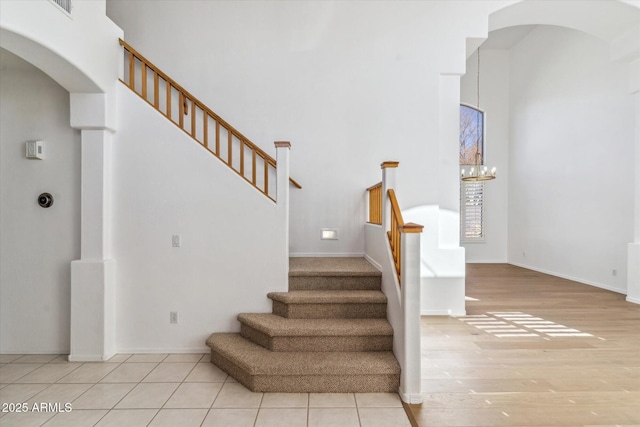 staircase with tile patterned flooring and a notable chandelier