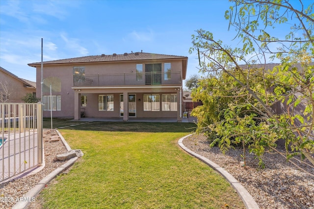 back of property with a lawn and a balcony