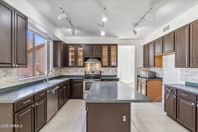 kitchen with dark brown cabinetry, tasteful backsplash, stainless steel appliances, and a center island