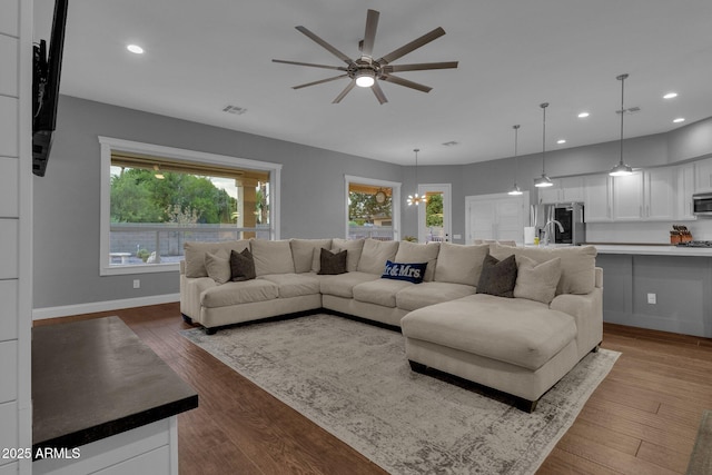 living room featuring hardwood / wood-style floors, ceiling fan with notable chandelier, and sink