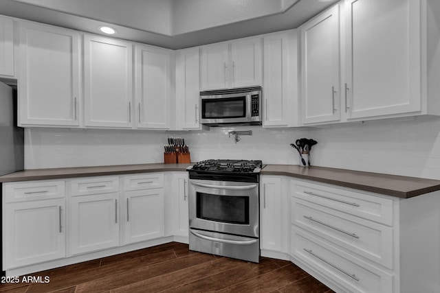 kitchen featuring decorative backsplash, white cabinets, and appliances with stainless steel finishes