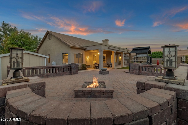 back house at dusk with a patio and an outdoor fire pit