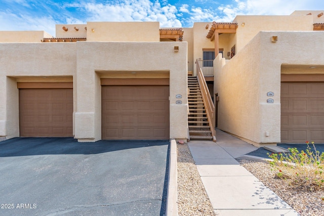 view of front of home featuring stairs, driveway, a tiled roof, and stucco siding