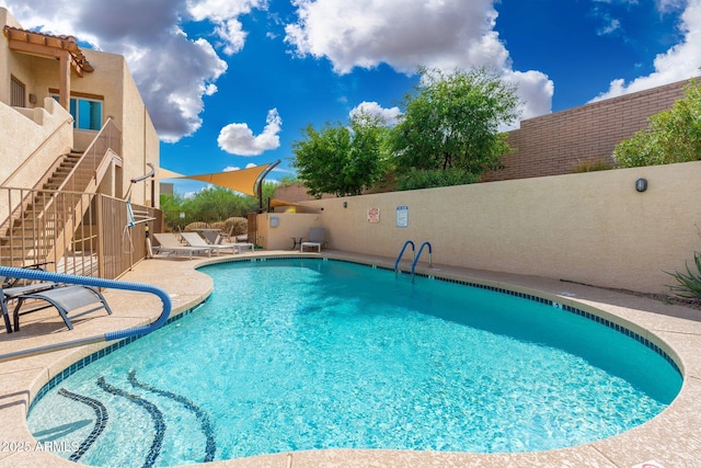 pool with a patio area, a fenced backyard, and stairway