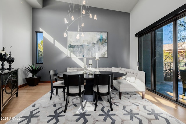 dining area featuring light wood-type flooring and high vaulted ceiling