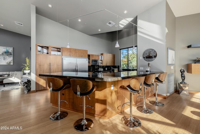 kitchen featuring a kitchen breakfast bar, a towering ceiling, stainless steel appliances, and decorative light fixtures