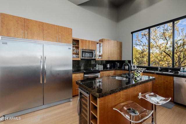 kitchen featuring a center island with sink, sink, stainless steel appliances, and light hardwood / wood-style flooring