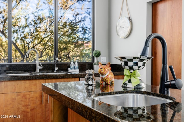 kitchen featuring hanging light fixtures, sink, and dark stone counters