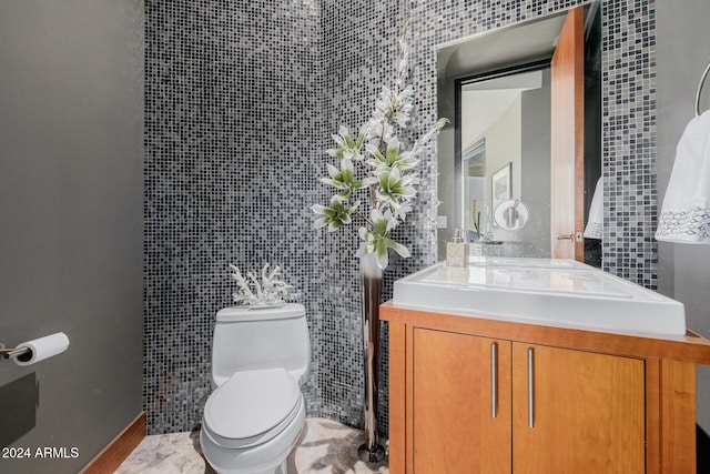 bathroom featuring vanity, toilet, and tile walls