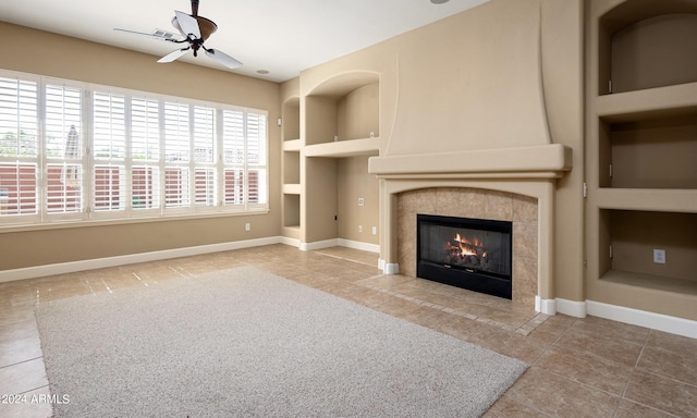 unfurnished living room featuring built in shelves, ceiling fan, tile patterned floors, and a tile fireplace