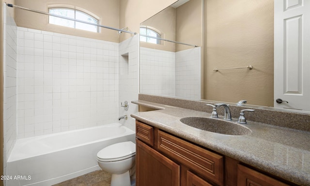 full bathroom featuring vanity, tiled shower / bath, and toilet