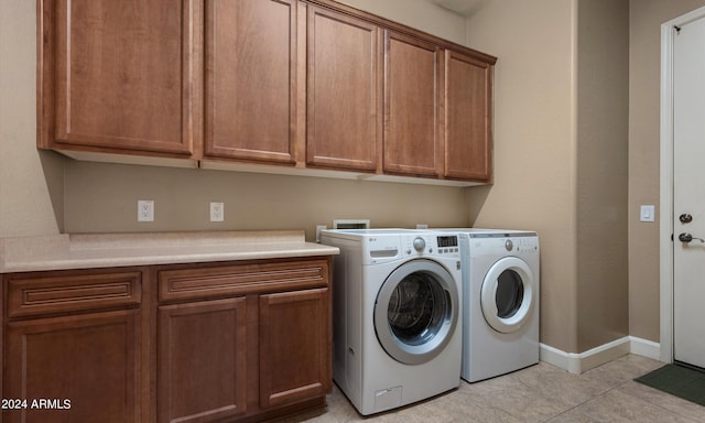 washroom featuring independent washer and dryer, cabinets, and light tile patterned flooring