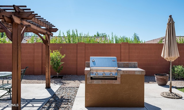 view of patio featuring a grill, a pergola, and exterior kitchen