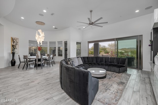 living room with a high ceiling, light hardwood / wood-style flooring, and ceiling fan