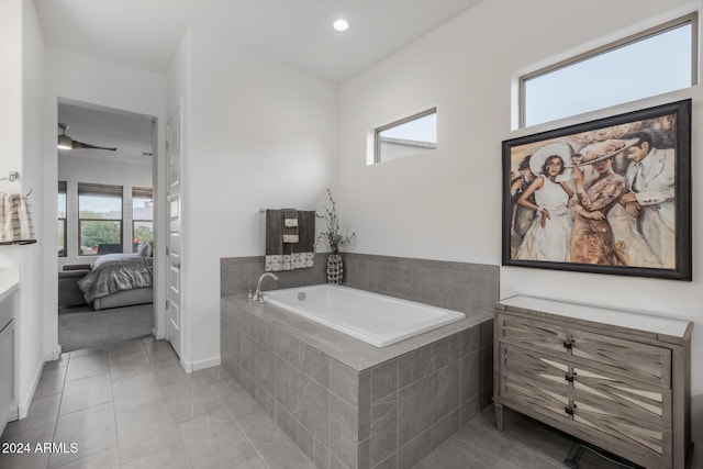 bathroom featuring tile patterned flooring, vanity, a healthy amount of sunlight, and tiled tub