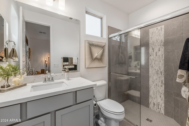 bathroom featuring vanity, toilet, and a shower with shower door