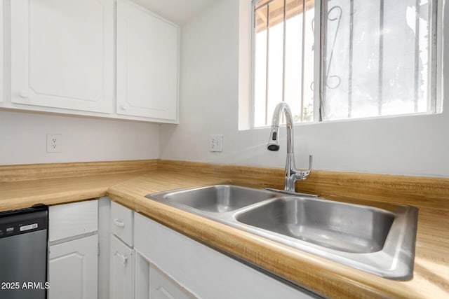 kitchen with plenty of natural light, sink, stainless steel dishwasher, and white cabinets