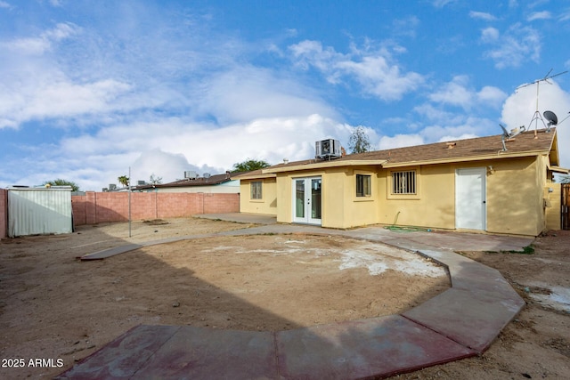 back of property with central AC and a patio