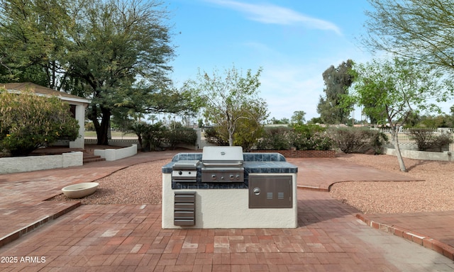 view of patio featuring a grill, fence, and an outdoor kitchen