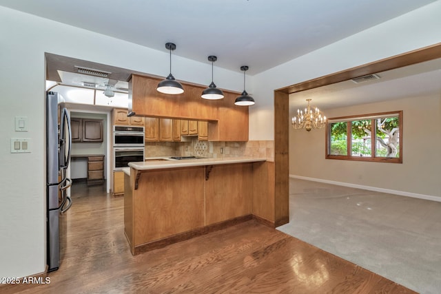 kitchen with tasteful backsplash, visible vents, a peninsula, stainless steel appliances, and light countertops