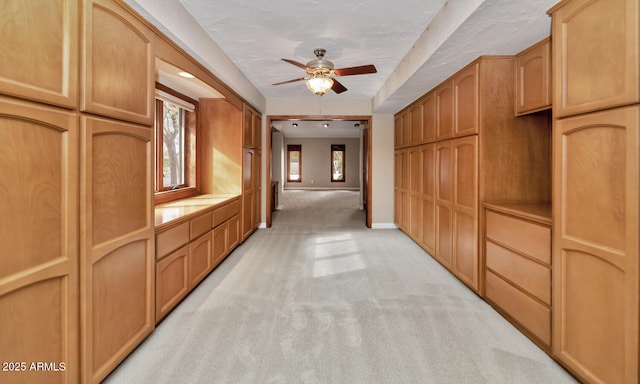 hallway with baseboards and light colored carpet