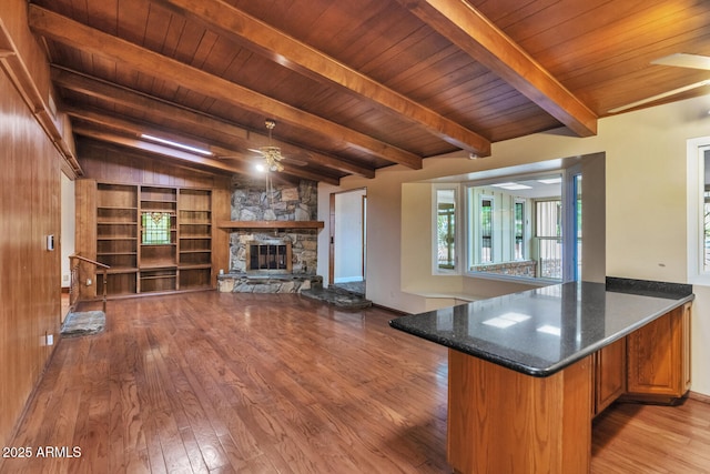 kitchen with a fireplace, lofted ceiling with beams, a ceiling fan, wood ceiling, and hardwood / wood-style flooring