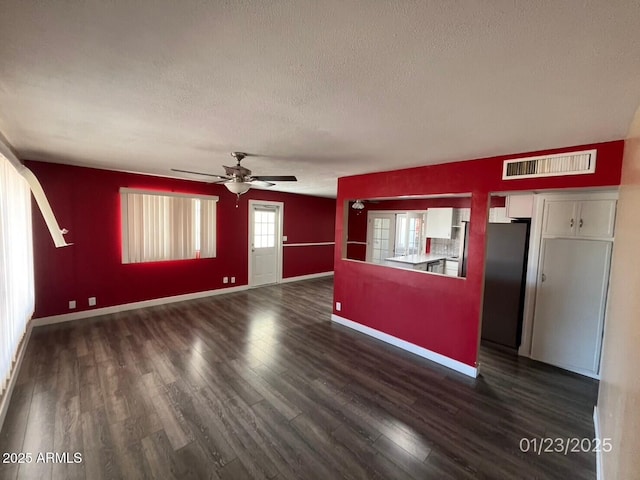 unfurnished living room featuring ceiling fan, dark wood-type flooring, and a textured ceiling