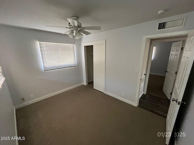 unfurnished bedroom featuring ceiling fan, dark carpet, and a closet