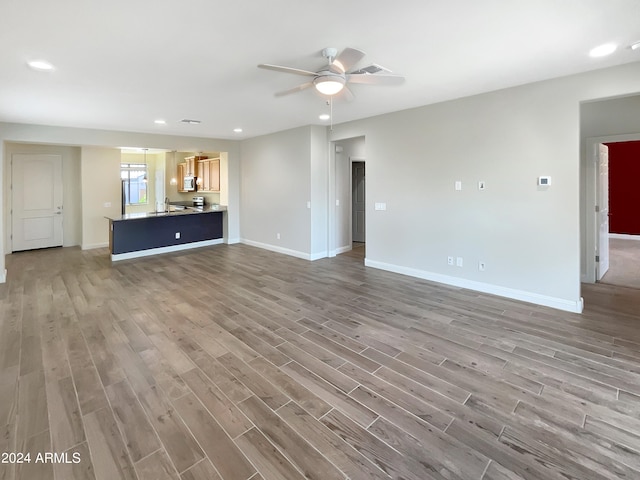 unfurnished living room featuring ceiling fan and hardwood / wood-style flooring