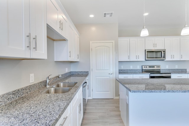 kitchen featuring white cabinets, stainless steel appliances, hanging light fixtures, and sink