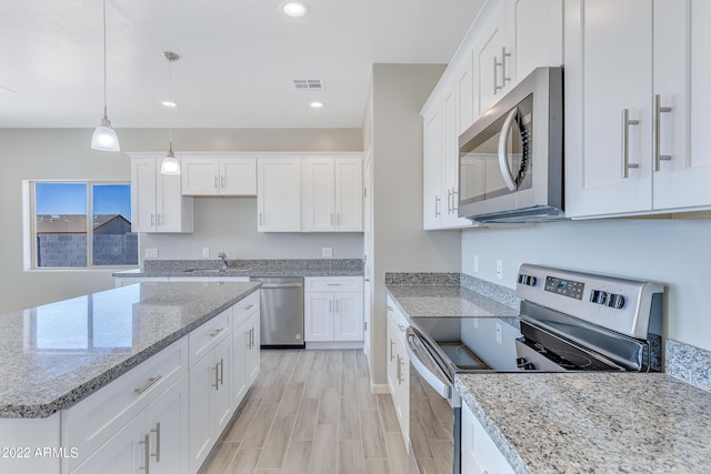 kitchen featuring white cabinets, appliances with stainless steel finishes, light stone countertops, and pendant lighting