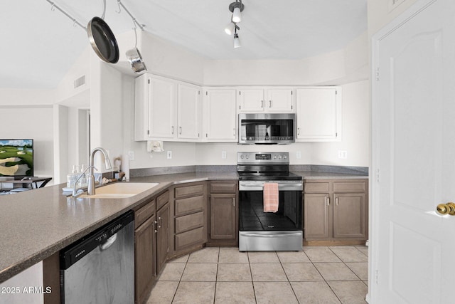 kitchen featuring light tile patterned floors, rail lighting, stainless steel appliances, white cabinets, and sink