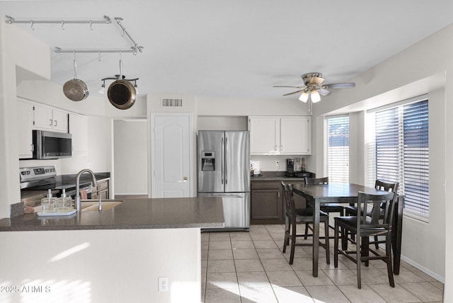 kitchen featuring ceiling fan, white cabinets, stainless steel appliances, and light tile patterned flooring