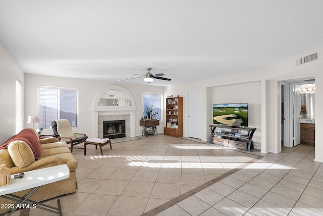 living room with ceiling fan, light tile patterned flooring, and a tiled fireplace