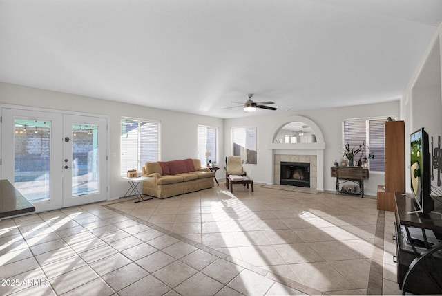 living room with ceiling fan, light tile patterned floors, a fireplace, and french doors