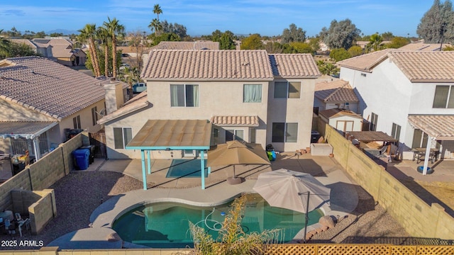 rear view of property featuring a pergola, a patio area, and a fenced in pool