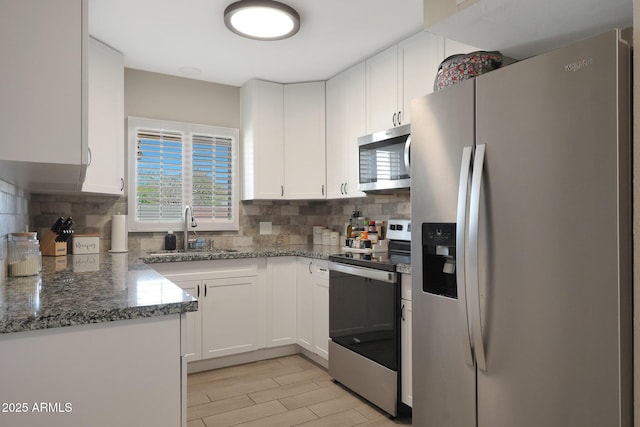 kitchen featuring backsplash, white cabinetry, stainless steel appliances, and a sink