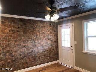 doorway featuring a healthy amount of sunlight, ceiling fan, and brick wall