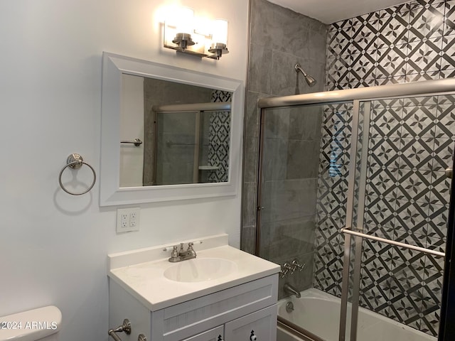 full bathroom with combined bath / shower with glass door, vanity, and toilet