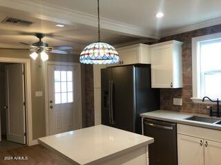 kitchen featuring ceiling fan, sink, white cabinetry, decorative light fixtures, and black appliances