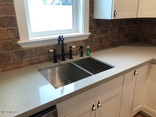 interior space featuring backsplash, sink, and white cabinetry