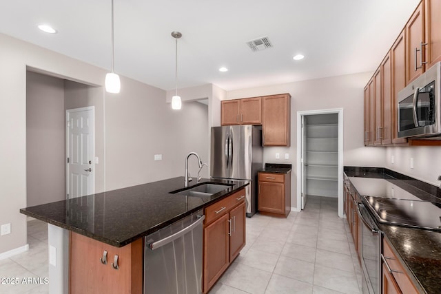 kitchen featuring stainless steel appliances, hanging light fixtures, a sink, visible vents, and brown cabinetry